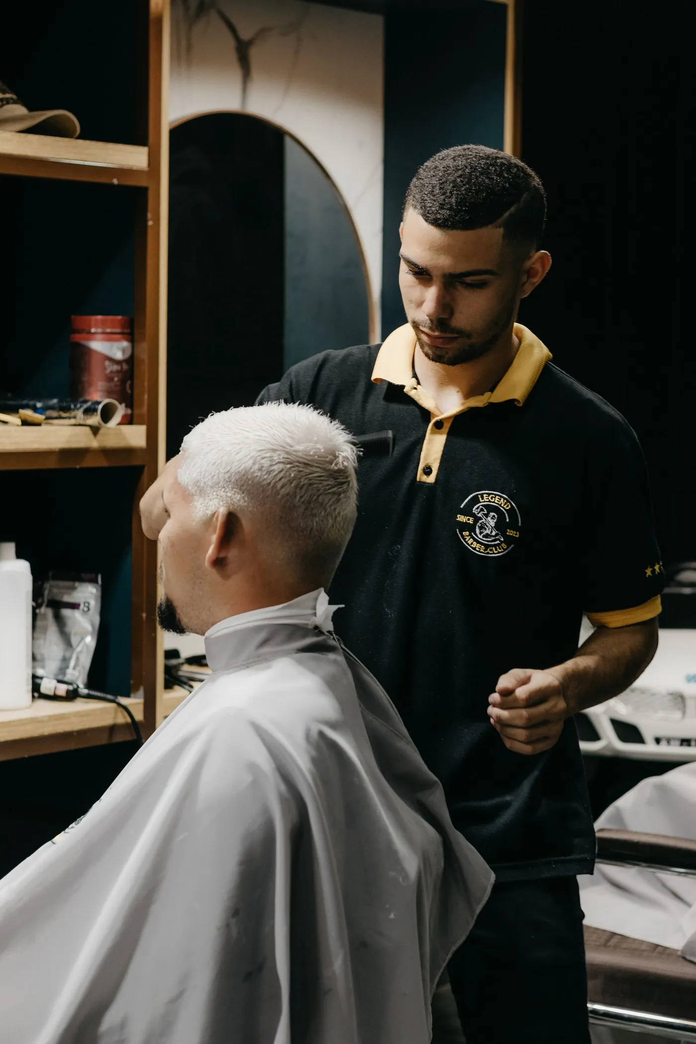 Thợ cắt tóc cho khách nam bên cột barber pole